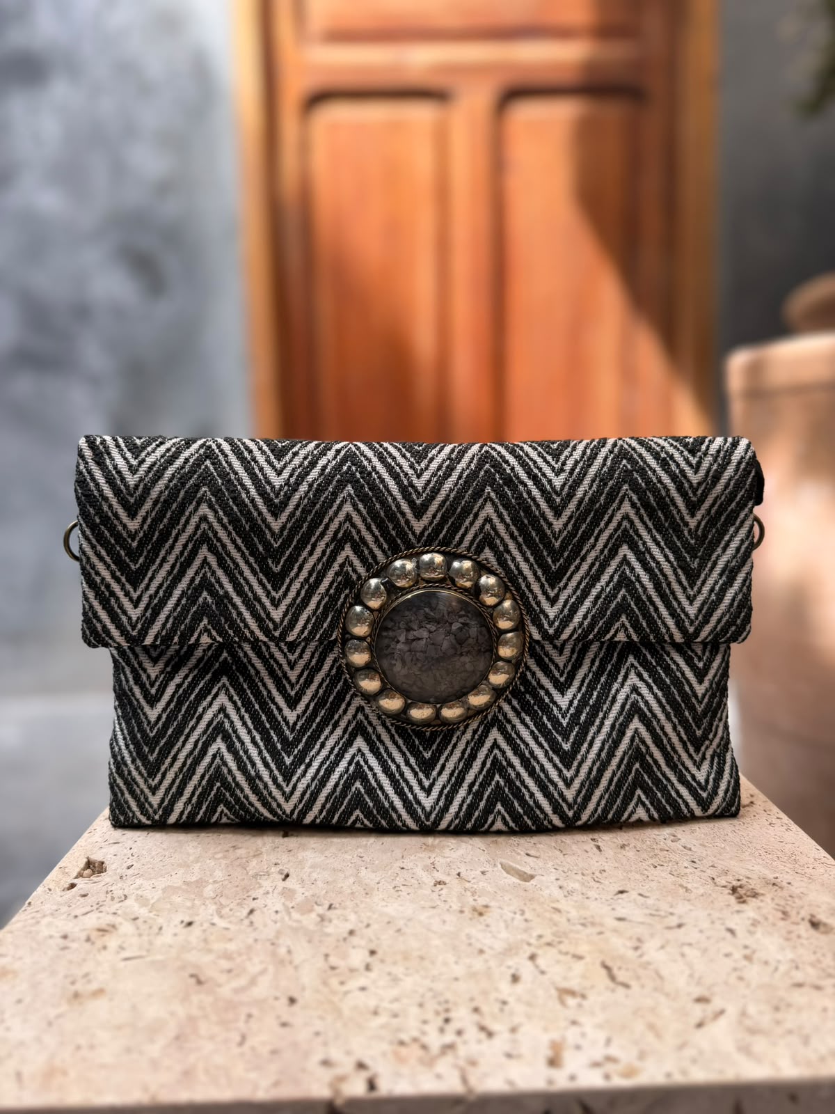Black-and-white chevron carpet bag with a smoky-toned circular centrepiece framed by metallic detailing