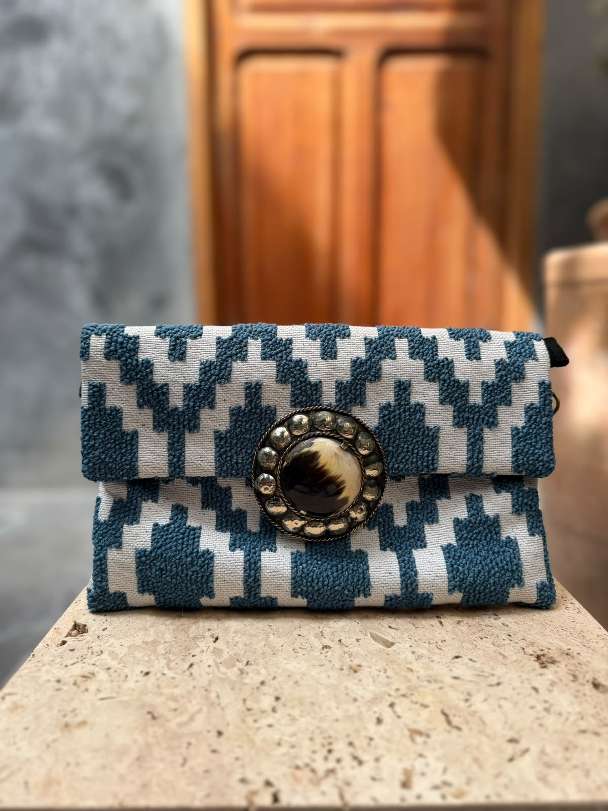 Blue-and-cream geometric carpet bag with raised blue motifs and a dark-and-cream circular centrepiece in a metallic surround
