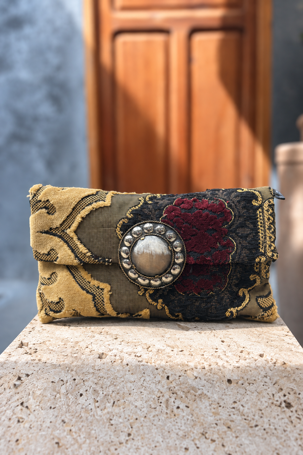 Venice Legzita carpet bag on a beige stone pedestal in front of a wooden doorway