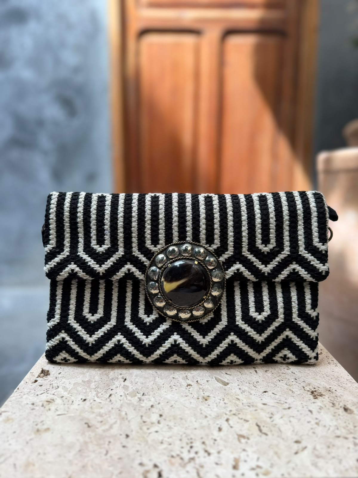 Black-and-white geometric carpet bag with a dark circular centrepiece, golden-coloured accent and metallic surround