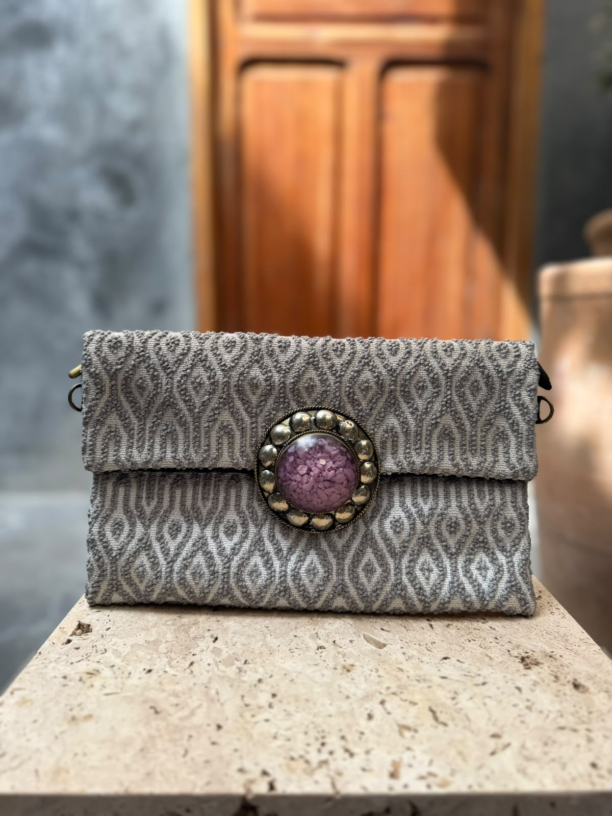 Silver-grey carpet bag with elongated diamond patterns and a purple circular centrepiece framed by metallic detailing