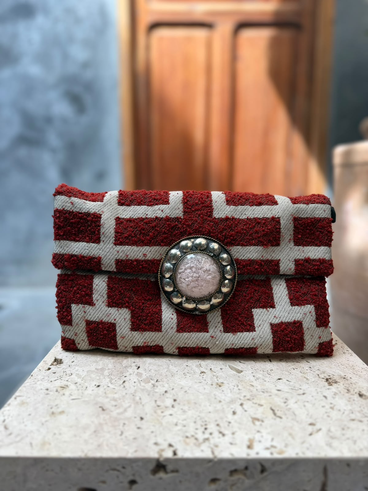 Burgundy-and-cream geometric carpet bag with raised burgundy shapes and a pale pink circular centrepiece framed by metallic detailing