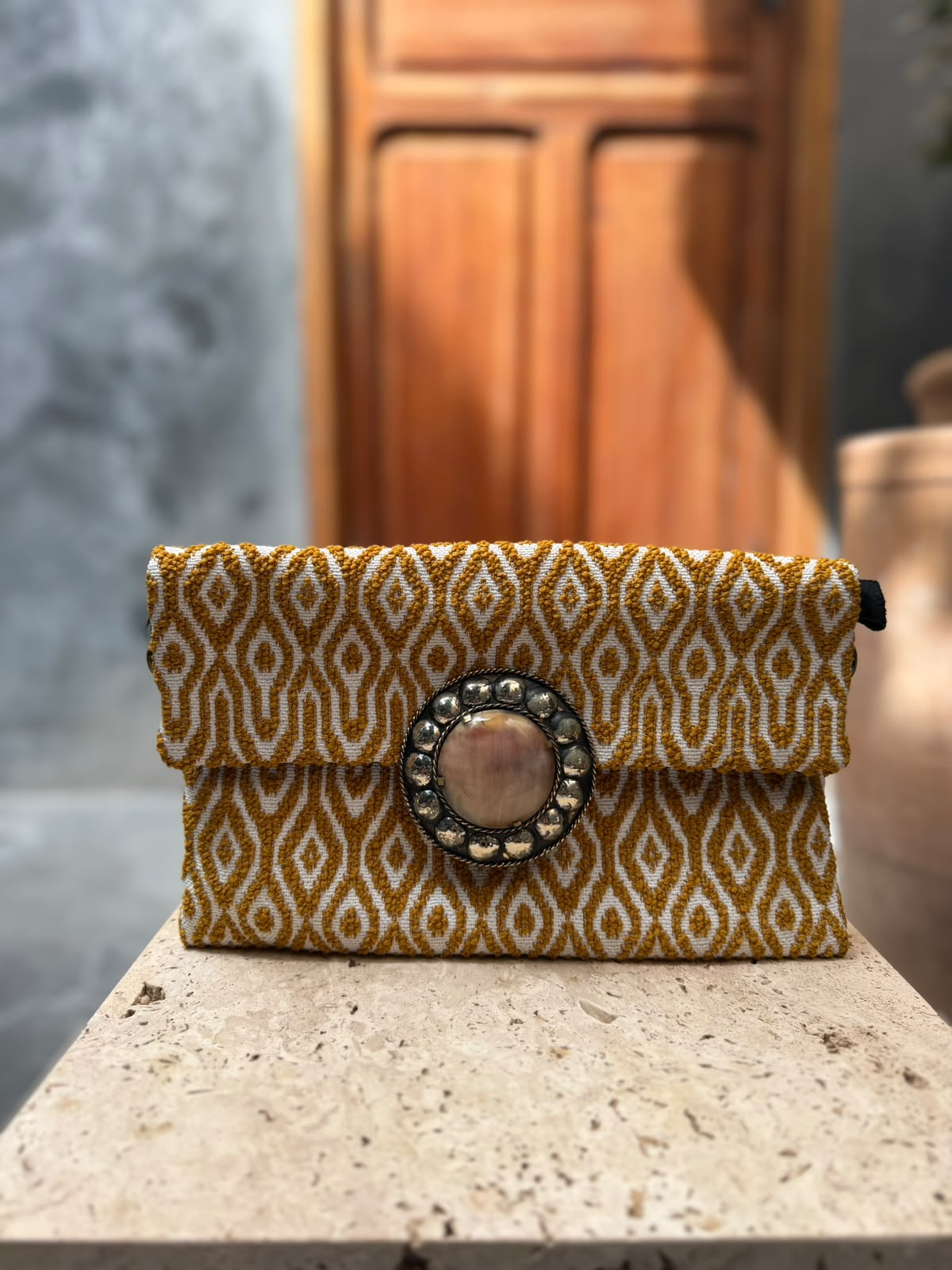Gold-and-cream carpet bag with elongated diamond patterns and a pale circular centrepiece framed by metallic detailing