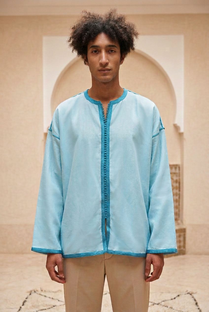 Male model wearing the smooth light blue Camel Shirt with turquoise decorative trim in a warm Moroccan riad