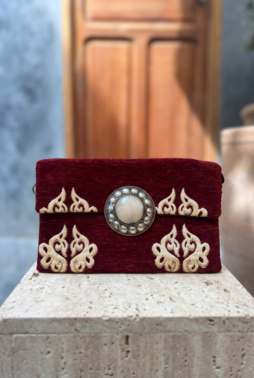 Burgundy and cream ornamental carpet clutch on a stone ledge