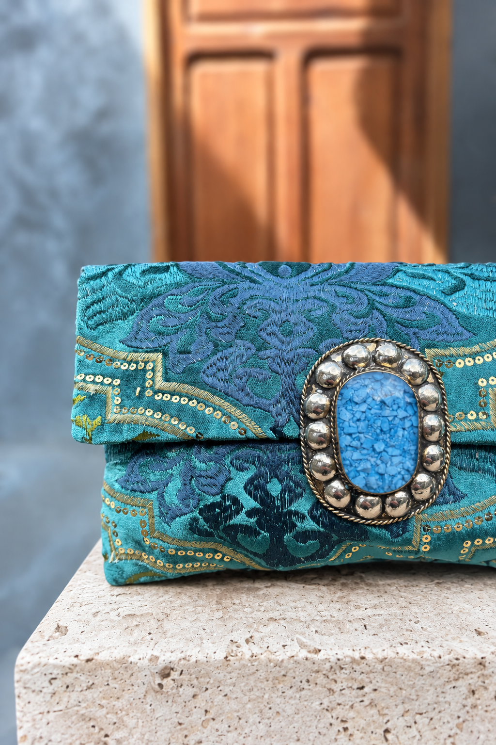 Close-up of Turquoise paradise's blue oval centrepiece and ornate teal fabric with matching stone-pedestal background