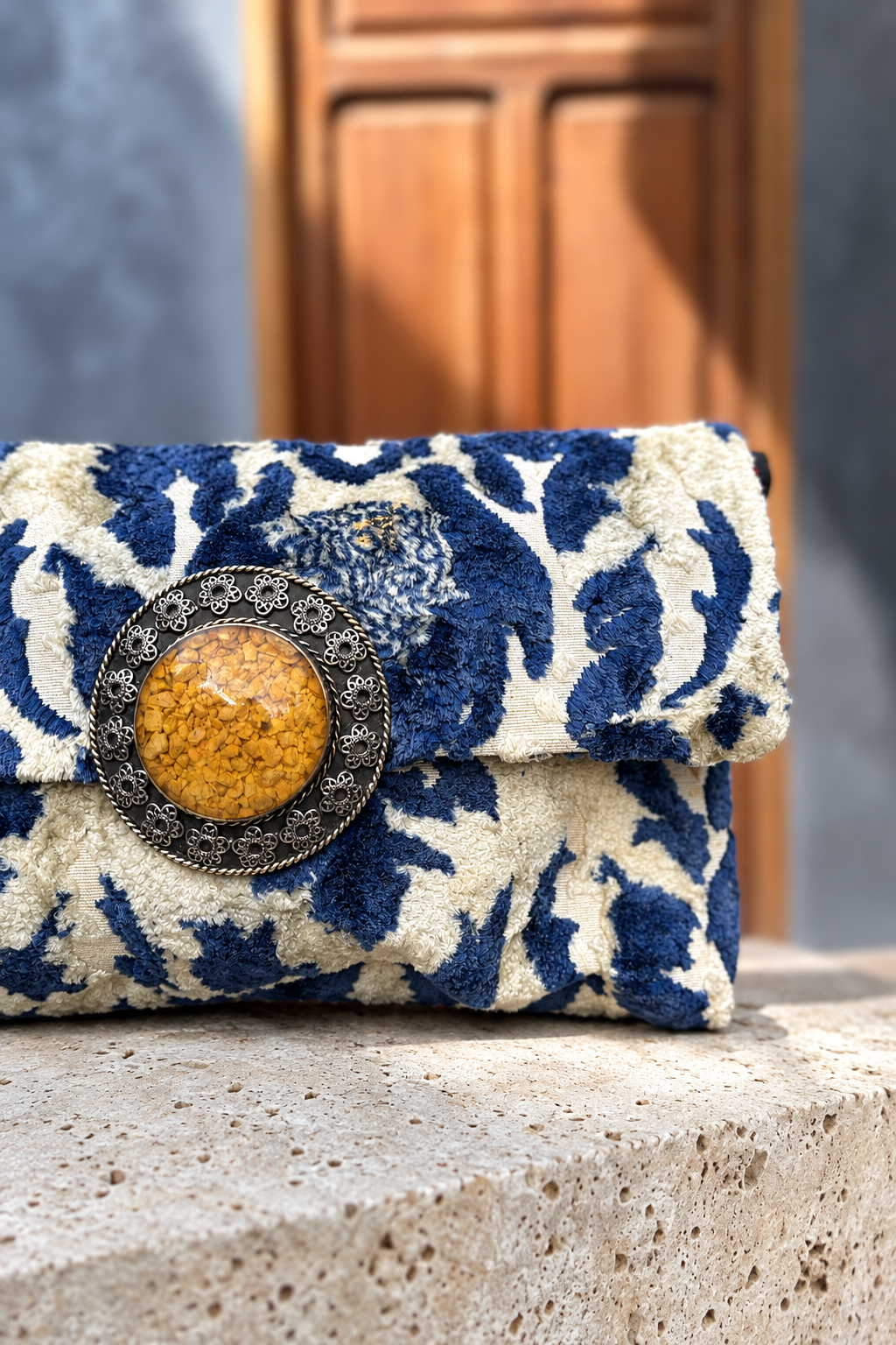 Close-up of Sky Silver Bag's yellow centrepiece and blue-and-ivory textured fabric with matching wooden doorway background