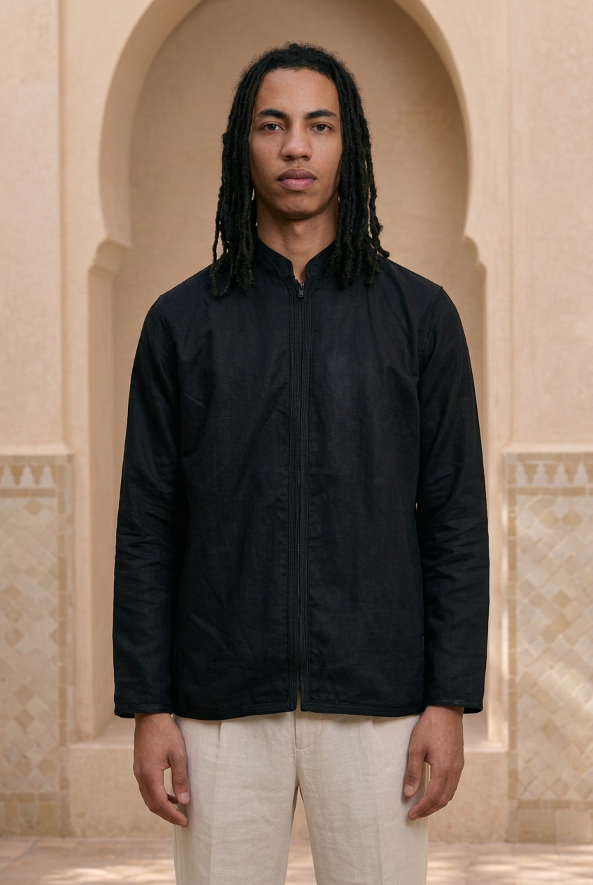 Model wearing the black Todra Shirt in a softly lit Moroccan riad with warm sand-and-cream walls