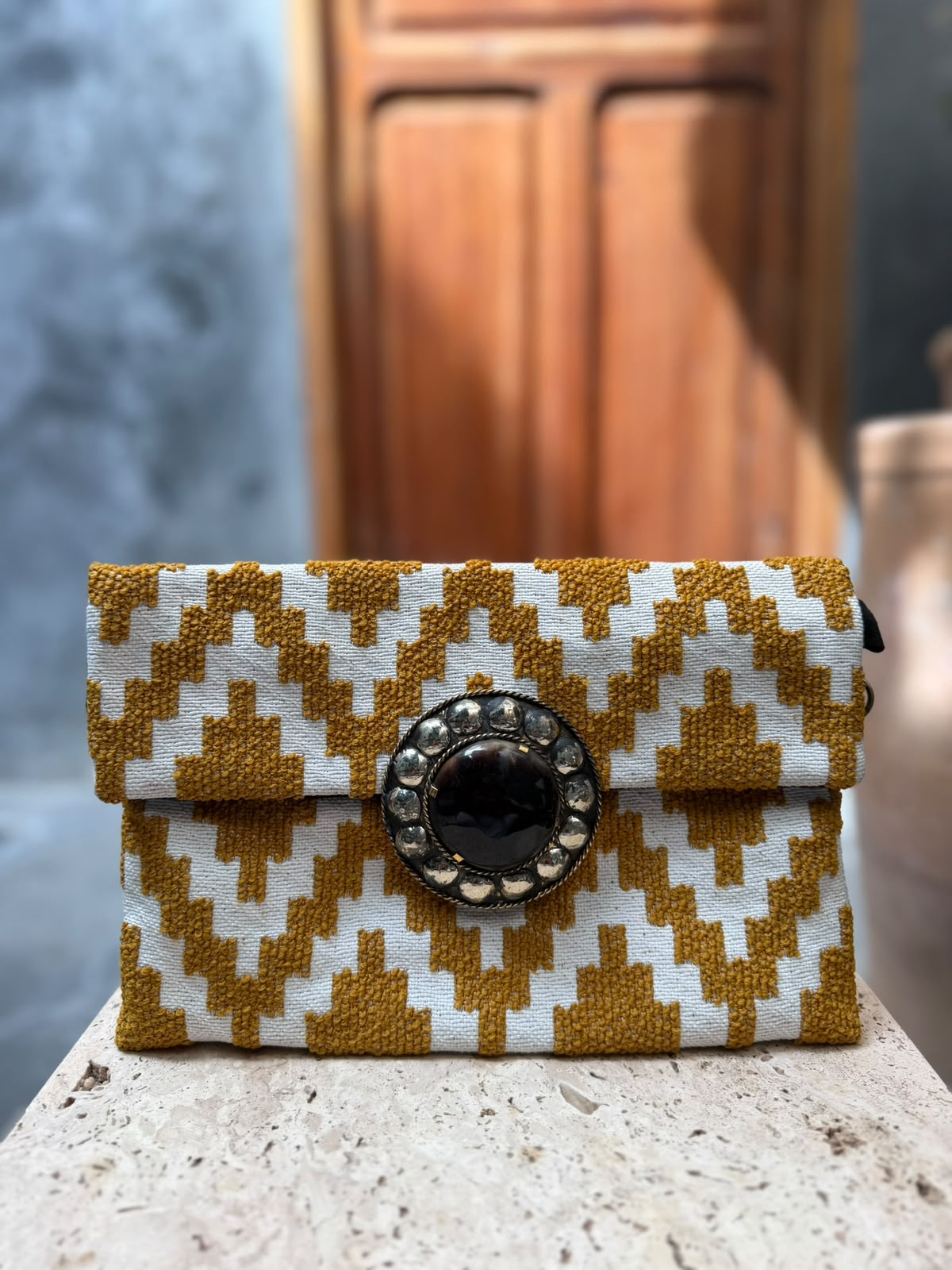 Mustard-and-cream geometric carpet bag with raised motifs and a dark circular centrepiece in a metallic surround